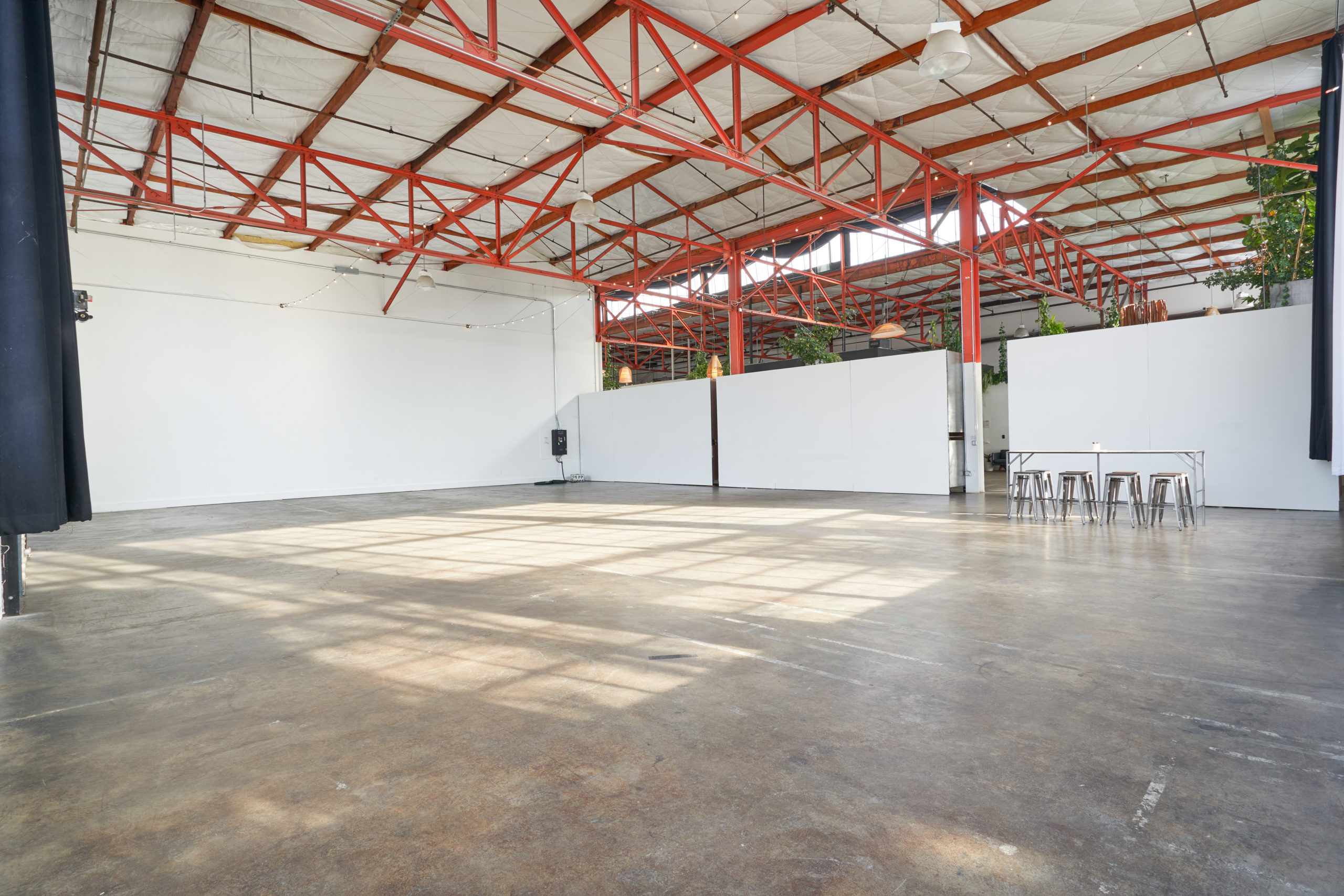 A view of the white walls and the industrial orange beams on the ceiling of Studio 5. There is a small table and chairs on the left of the best multiple set studio rental Berkeley has to offer with 3,700 square feet of space.