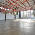 Expansive view of Studio 5 with 3,700 square feet of space, a large wall of windows, and orange, industrial ceiling beams that make it a spacious multiple set studio rental Berkeley has to offer.