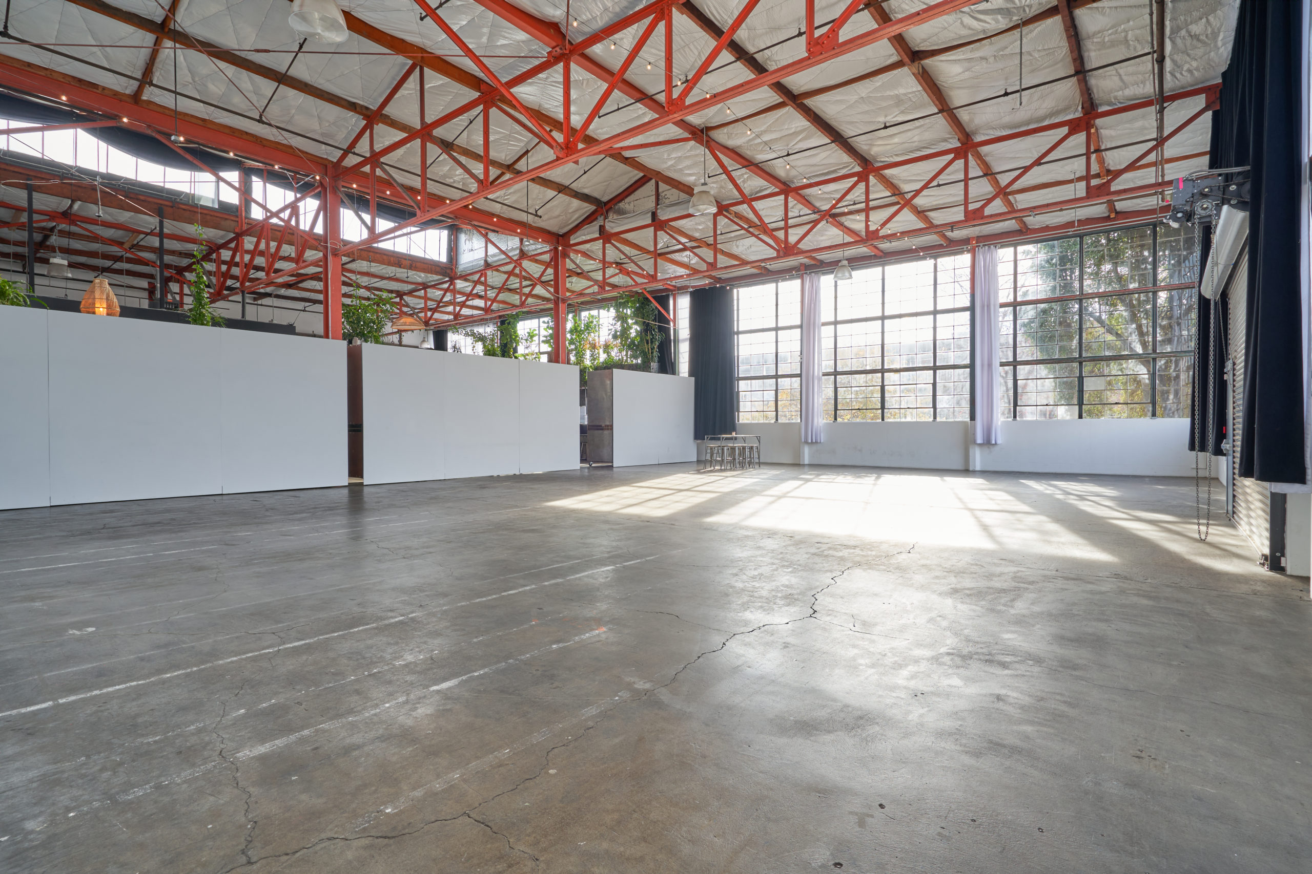 Expansive view of Studio 5 with 3,700 square feet of space, a large wall of windows, and orange, industrial ceiling beams that make it a spacious multiple set studio rental Berkeley has to offer.