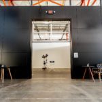 View of Studio 6 and the 1000 square foot space for this production studio rental. Featuring a black wall with 100 amps of power, there is a large entranceway that has a set of tables and chairs on either side.