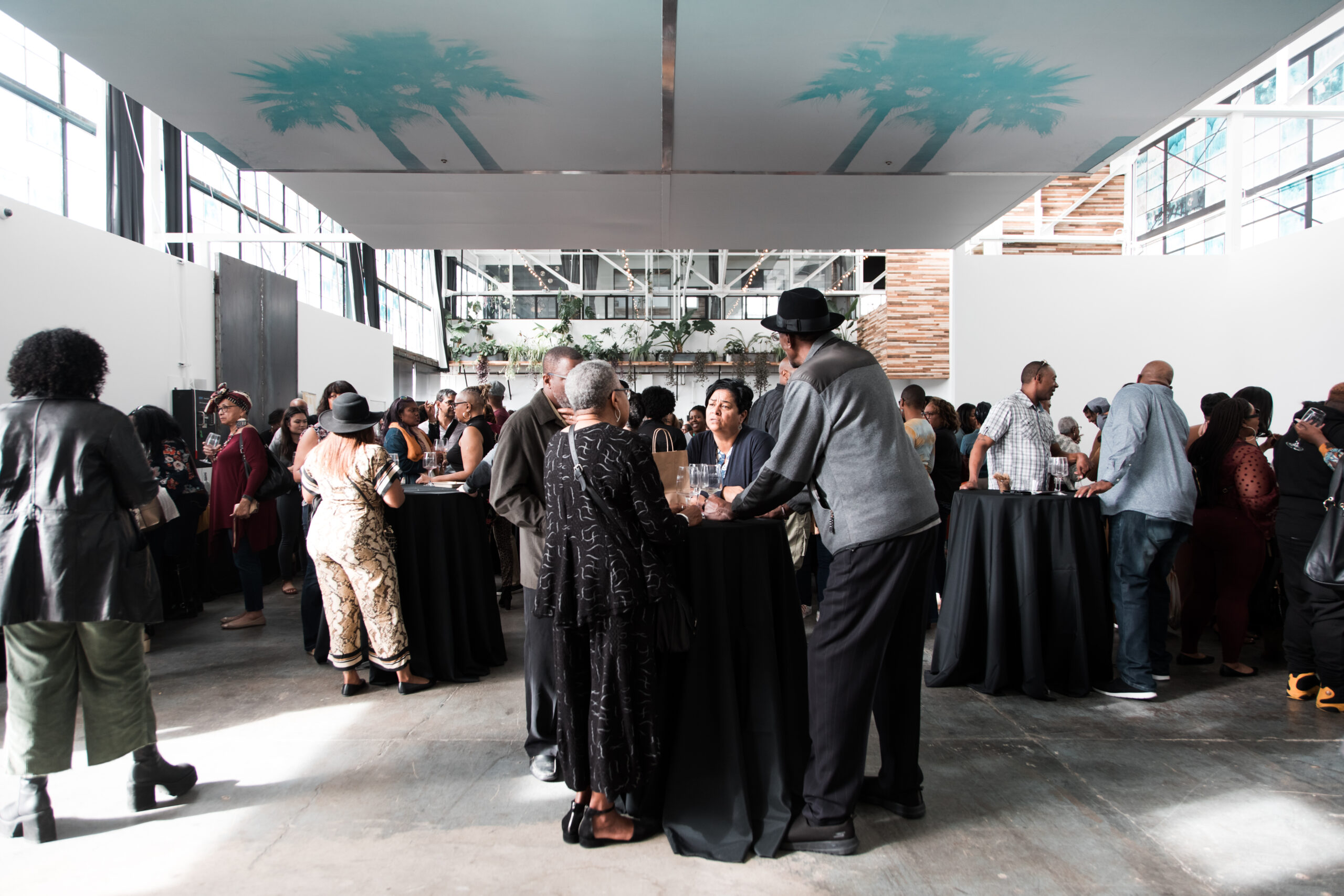 A creative space in San Francisco hosting an event with black hightop tables and crowds of people.